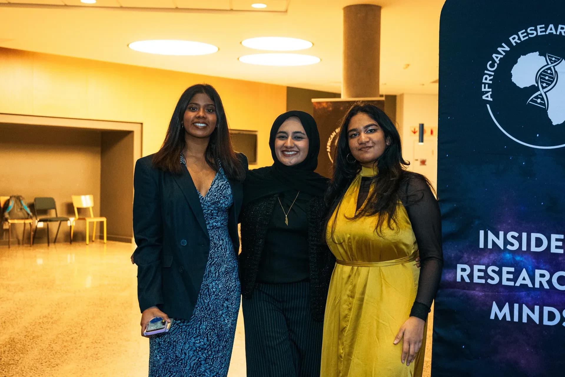 Three ARS members beside the Inside the Researcher's Minds event banner